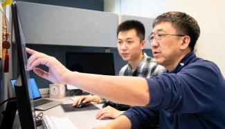 An image of Ying Xu and student at a computer